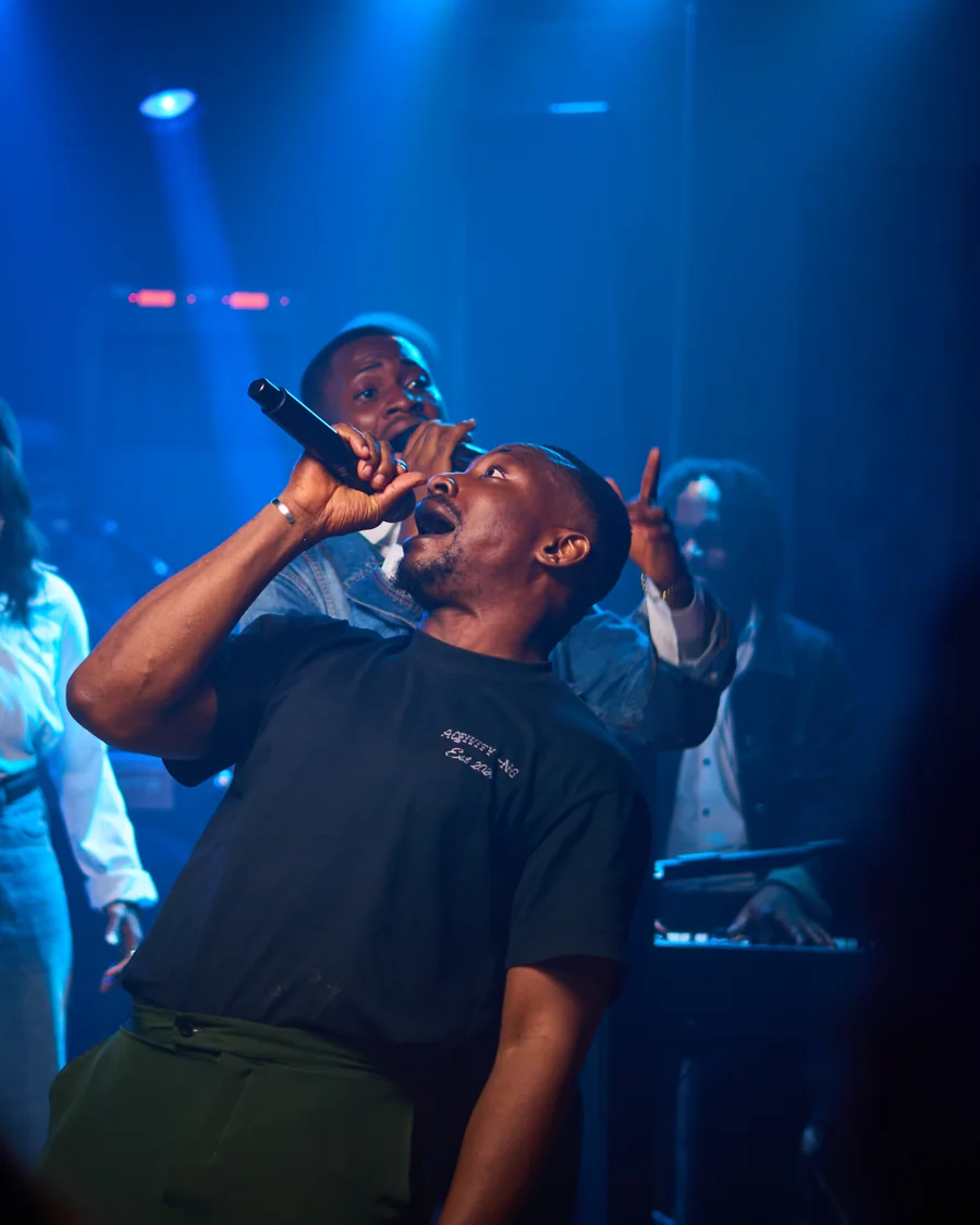 Richard Michael ministering under blue stage light, head lifted, with Jesus Breed behind him
