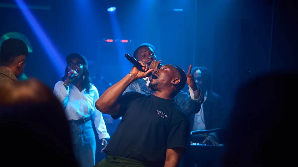 Richard Michael ministering under blue stage light, head lifted, with Jesus Breed behind him